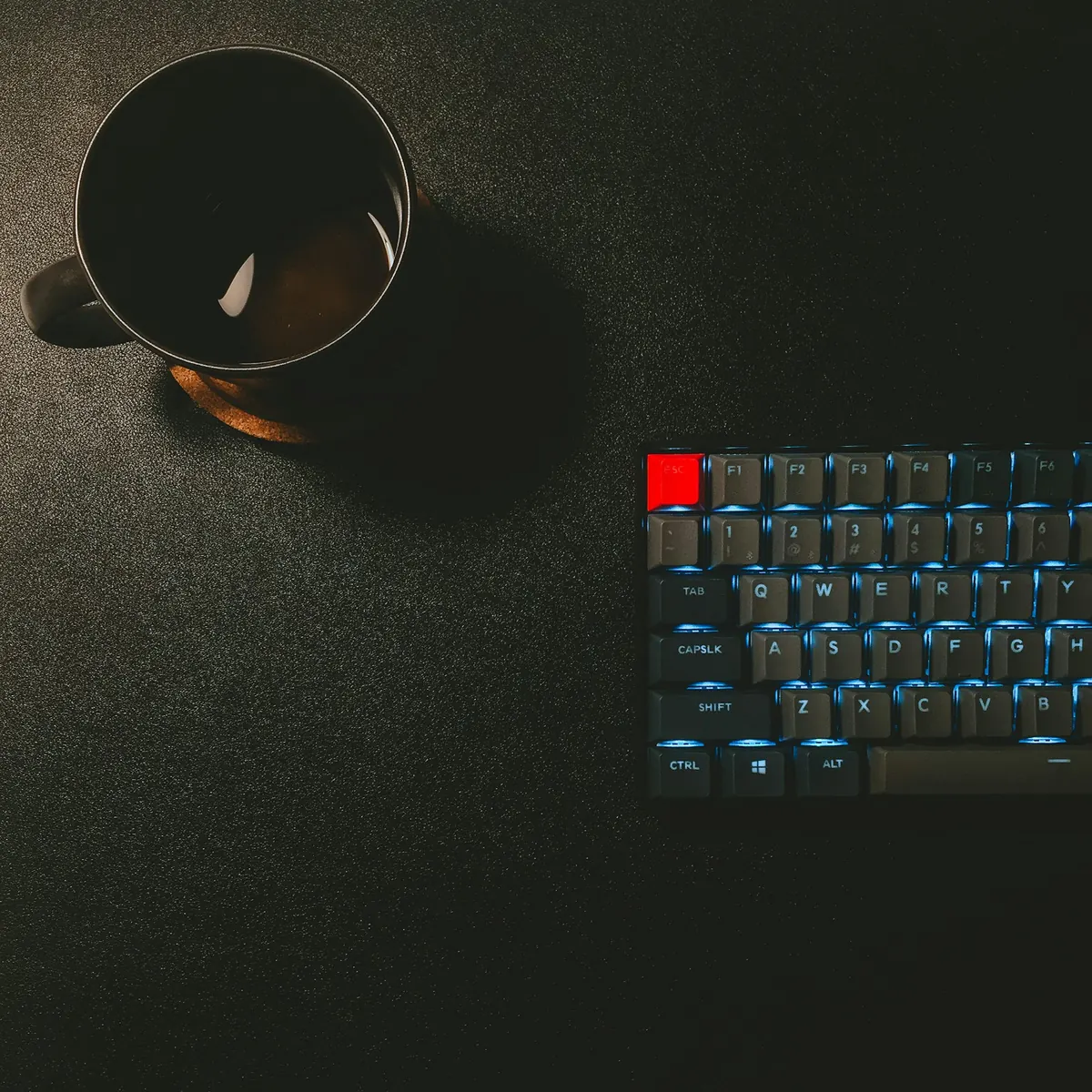 Caneca preta ao lado de teclado mecânico
