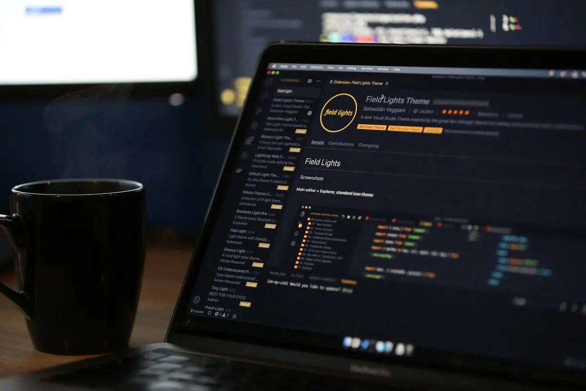 Código no monitor ao lado de uma caneca