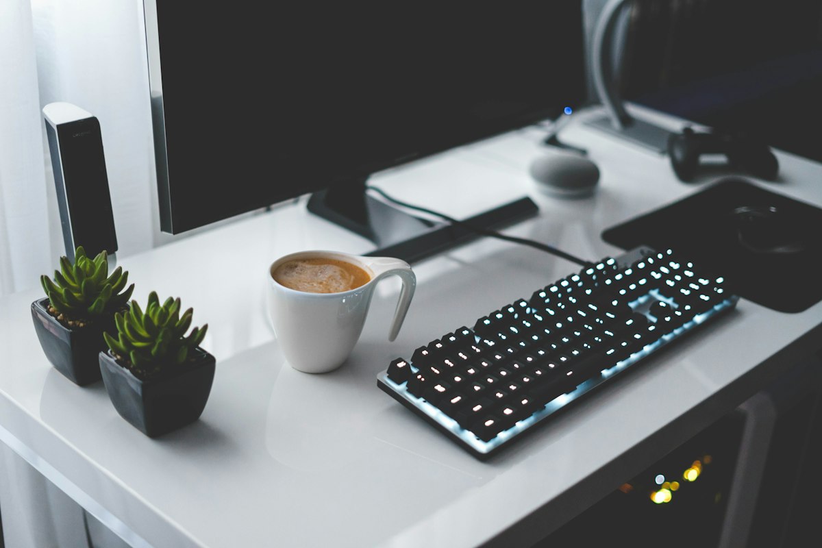 Mesa escura com caneca e teclado iluminado